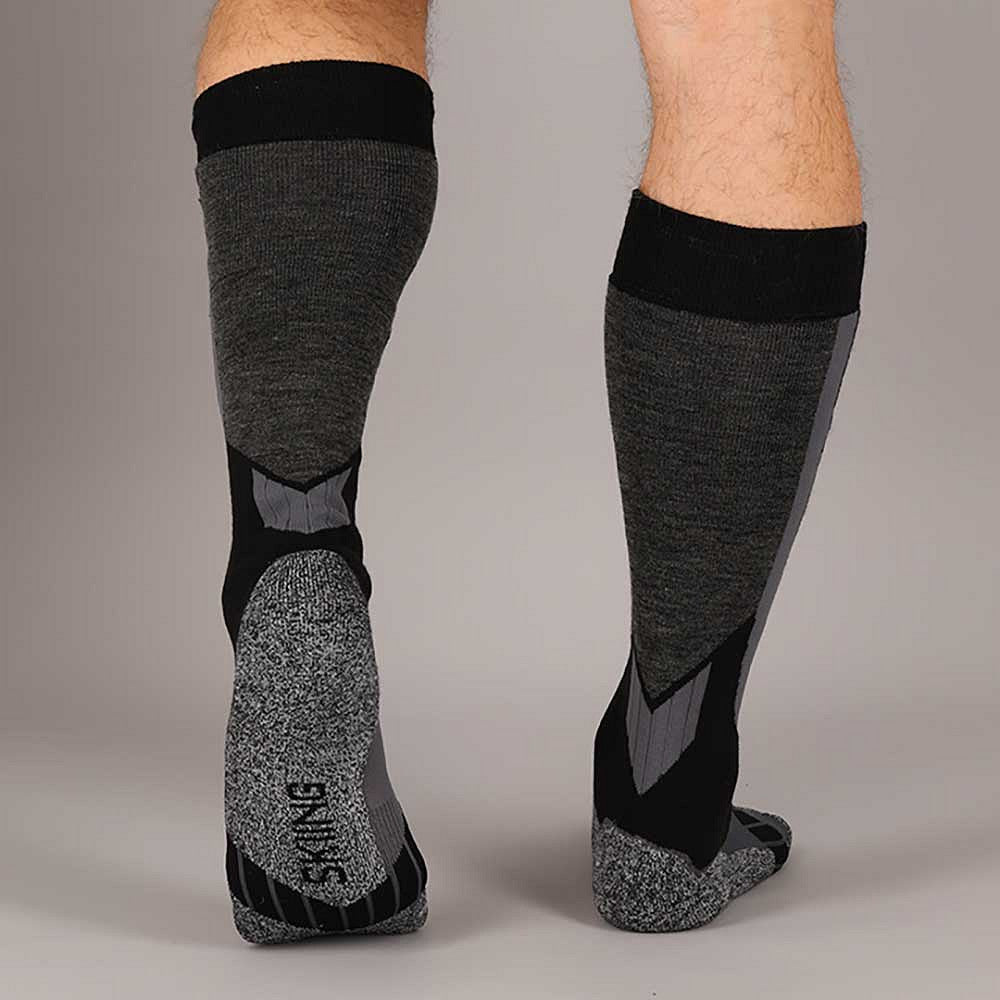 Volwassene draagt Xtreme skisokken zwart grijs tijdens het skiën op de piste