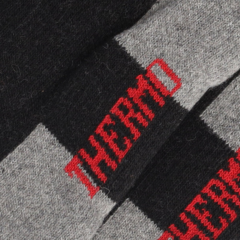 Close-up van zwart en grijs gestreepte stof met opvallende rode THERMO-stiksels - ideaal voor Apollo Thermo Wandelsokken Unisex 3-pack, gemaakt van een gerecyclede wolmix voor warme sokken of wandelsokken.