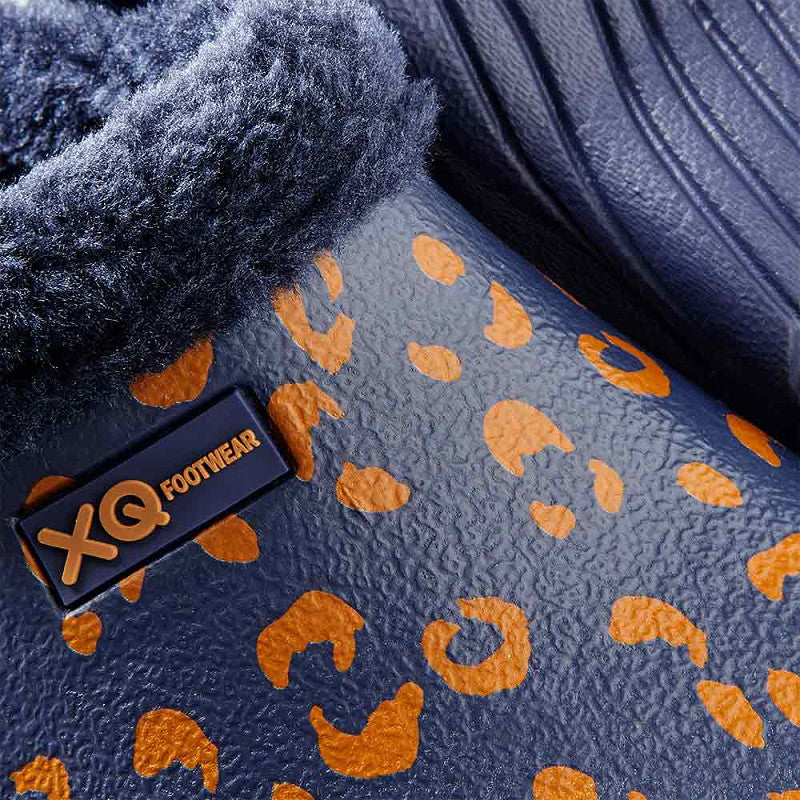 Close-up van een XQ Tuinklompen Dames Met Bontje - Luipaardprint Navy schoen met oranje luipaardvlekken, gezellige donkerblauwe voering en een XQ FOOTWEAR label, die de stijlvolle, warme details van deze gevoerde tuinklompen benadrukken.