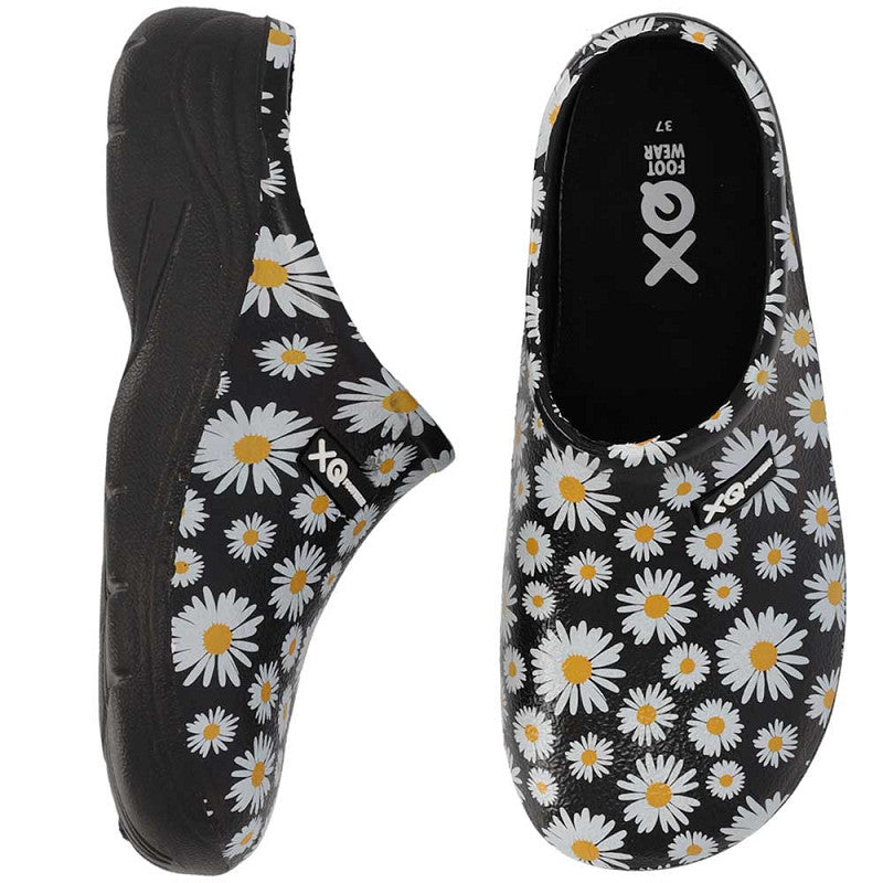 De XQ Tuinklompen Dames met Margrietjesprint zijn zwarte slip-on tuinklompen met een witte en gele margrietjesprint, van opzij en van boven gezien. Ze zijn gemaakt van lichtgewicht EVA-kunststof, waterafstotend en hebben een zwarte binnenkant en zool, FOOT WEAR aan de binnenkant.