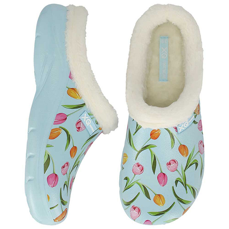 Een paar XQ Tuinklompen Dames - Met Bontje & Tulpenprint: lichtblauwe EVA slippers met een zachte witte voering en een levendig tulpendessin. De ene is van opzij te zien, de andere van boven.