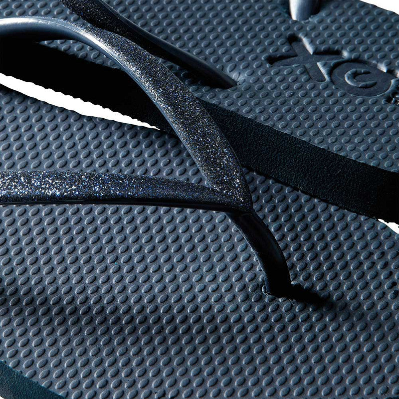 Vrouw draagt XQ dames slippers met navy glitterbandjes bij de zee