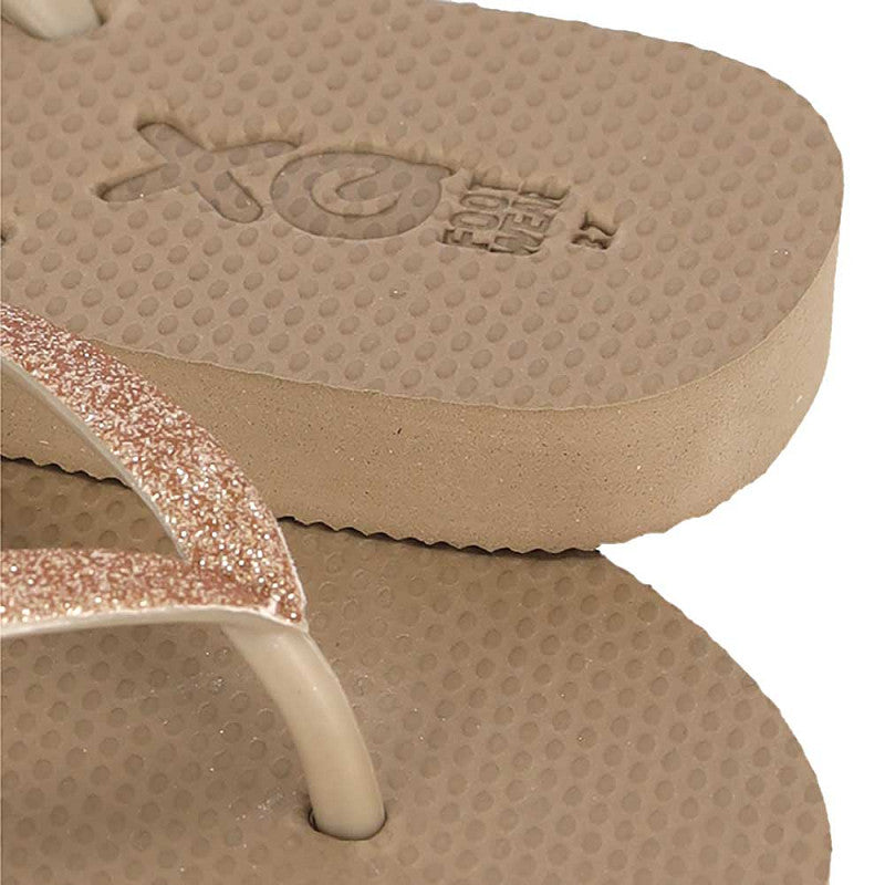 Vrouw draagt XQ dames slippers met taupe glitterbandjes op een terras