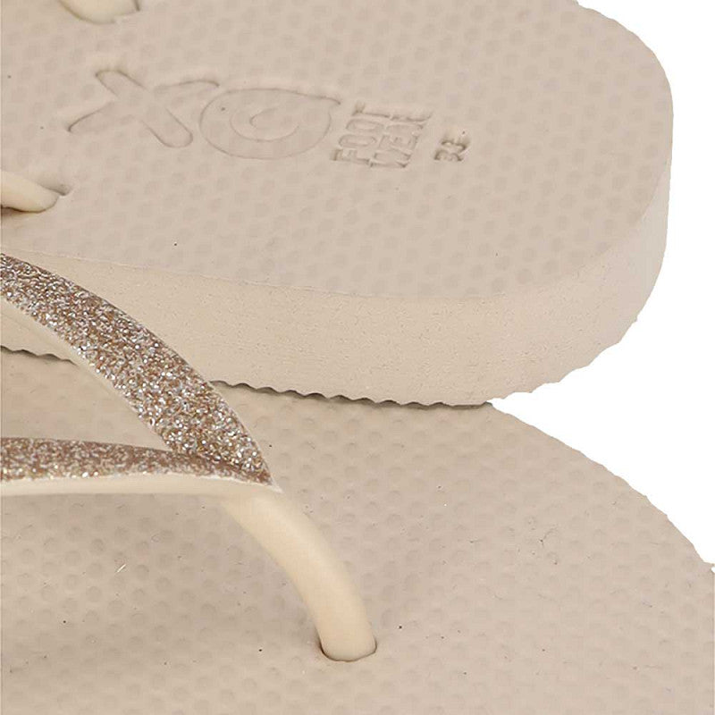 Vrouw draagt XQ dames slippers met zandkleurige glitterbandjes op het strand
