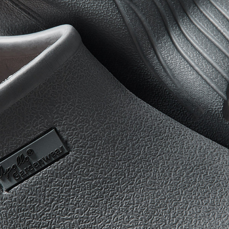 Close-up van de XQ Tuinklompen Dames Grijs instapmodel: een gestructureerde, donkergrijze, lichtgewicht tuinklomp met zichtbaar profiel, perfect voor comfort en praktisch als dames tuinklompen.