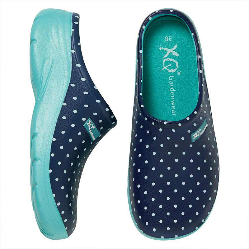 Een paar XQ Tuinklompen Dames - Lichtgewicht & Stippenprint in marineblauw met witte stippen en lichtblauwe zolen. De ene schoen is van opzij te zien, de andere van boven, beide met het KLOGS merklabel. Gemaakt van lichtgewicht EVA.
