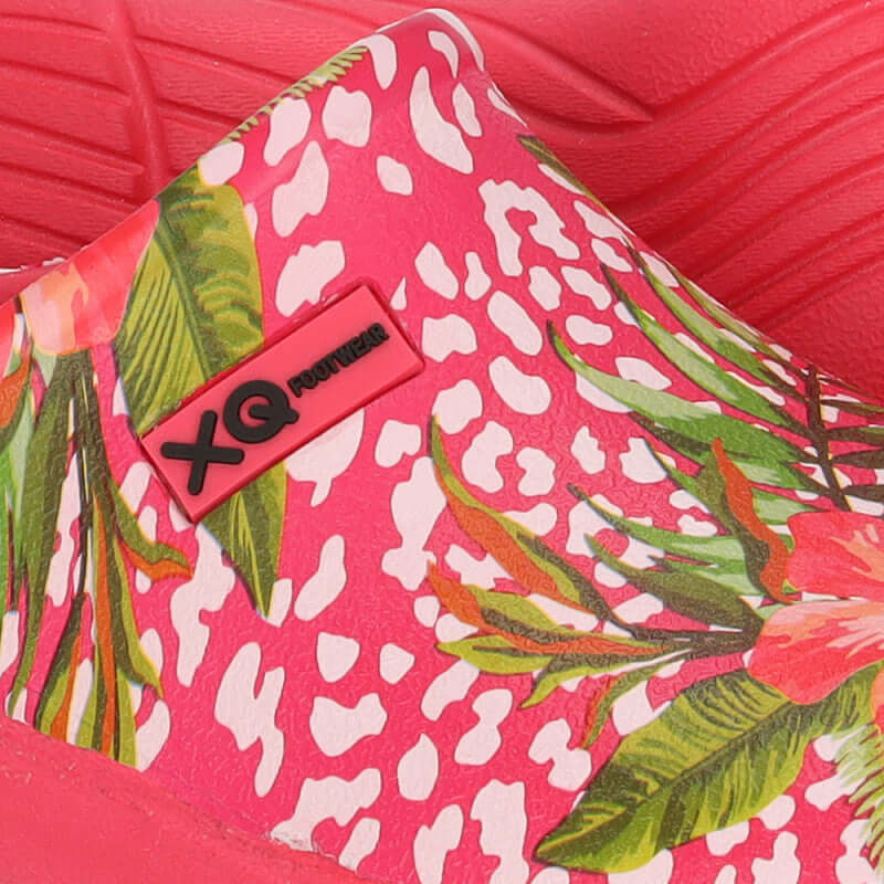 Vrouw draagt XQ instapklompen met fuchsia bloemenprint in de tuin