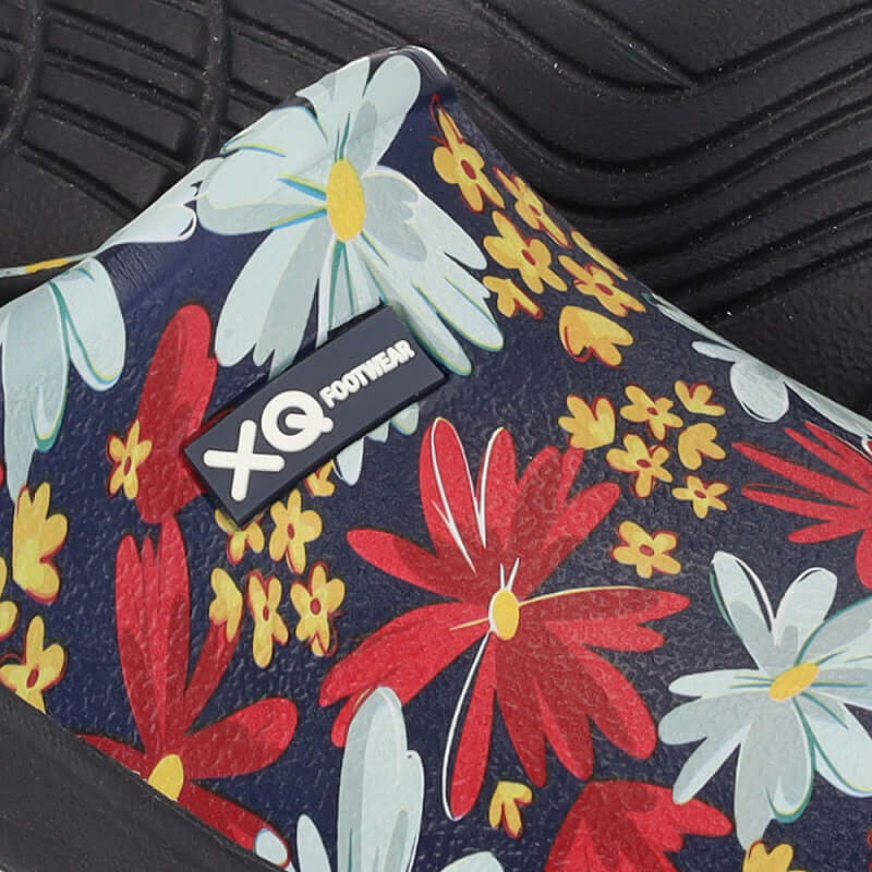 Vrouw draagt XQ instapklompen met bloemenprint in de tuin