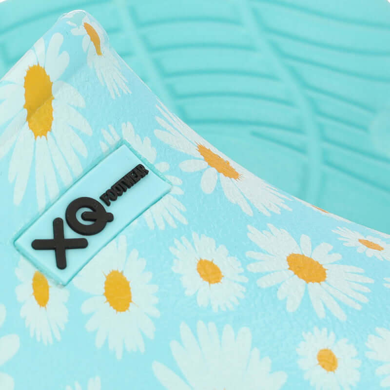 Vrouw draagt XQ instapklompen met aqua margrietjesprint in de tuin