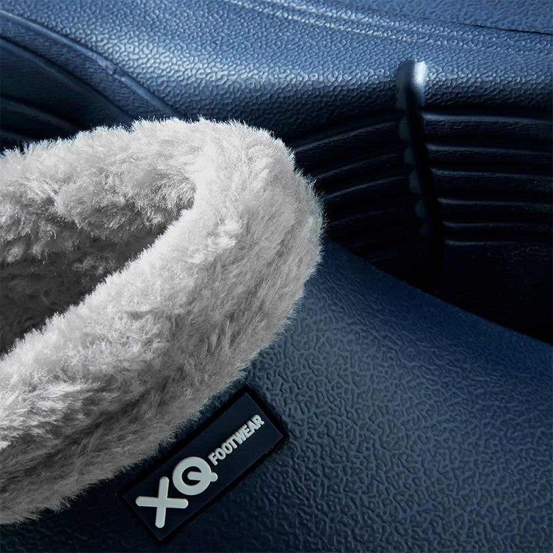 Close-up van de XQ Tuinklompen Heren Met Bontje Navy - Instapmodel & Lichtgewicht, met een gestructureerd marineblauw oppervlak, zachte grijze fleece voering, waterafstotende afwerking en zichtbaar XQ FOOTWEAR label op de zijkant.