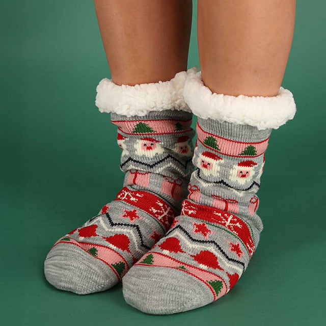 Vrouw draagt grijze Apollo x-mas sokken tijdens gezellige kerstdagen thuis bij de open haard