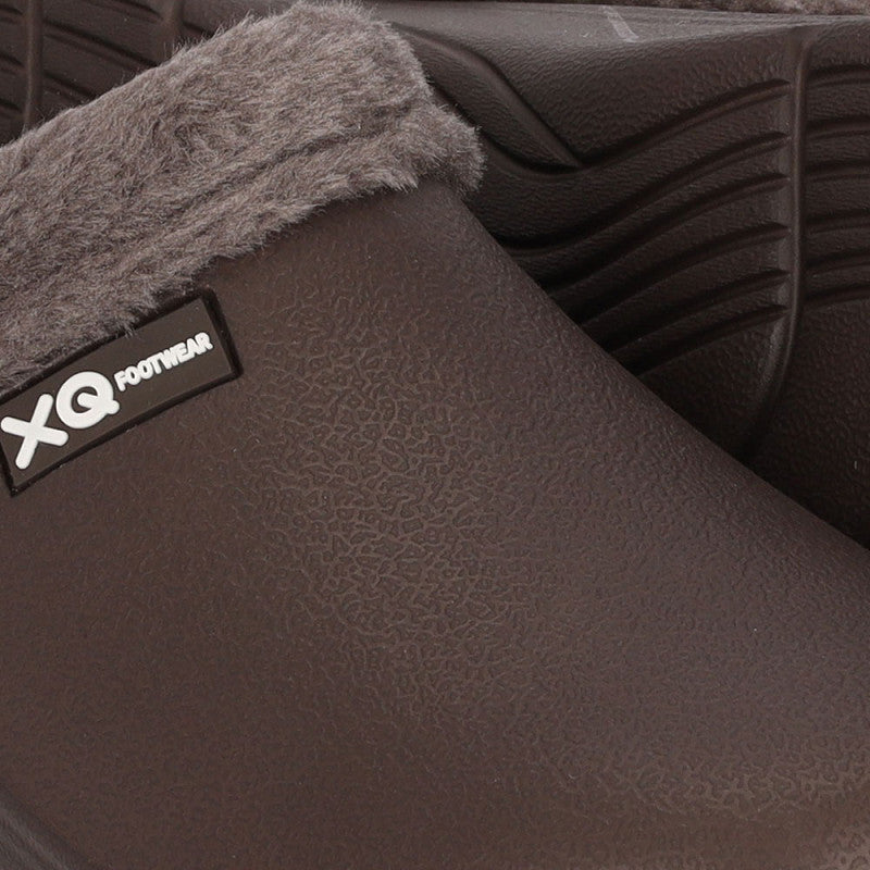 Close-up van XQ Tuinklompen Heren Met Bontje Bruin - Instapmodel & Lichtgewicht, met bruine structuurklompen met grijze voering van imitatiebont, een zwart-wit zijlabel en een stijlvol golvend zoolpatroon voor comfort.