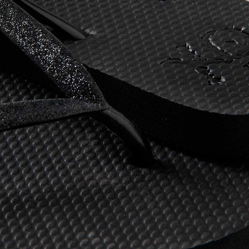 Vrouw draagt XQ dames slippers met zwarte glitterbandjes op een terras